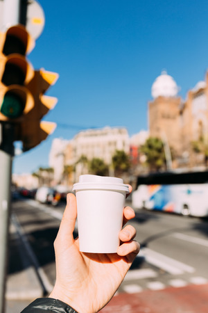 selective focus of male hand with paper cup, urban scene on background, barcelona, spainの写真素材