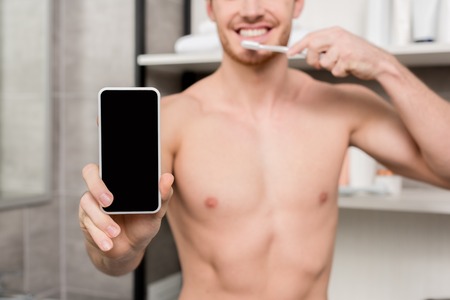 selective focus of man holding smartphone and brushing teethの写真素材