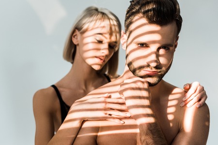 attractive girl hugging handsome shirtless man isolated on grey with shadows
