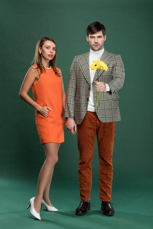 attractive couple in vintage clothes with flowers posing on green backgroundの写真素材
