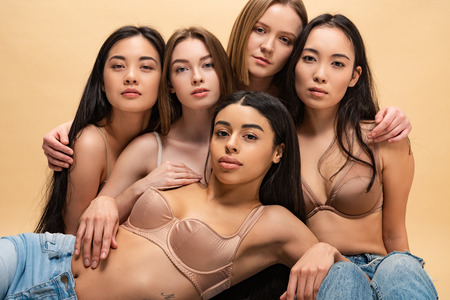 five pensive multicultural women posing at camera isolated on beigeの写真素材