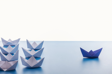 Paper boats on light blue surface on white backgroundの写真素材