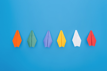 Flat lay with colorful paper planes on blue surfaceの写真素材
