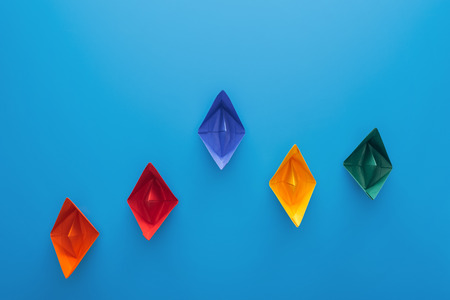 Top view of colorful paper boats on blue surface