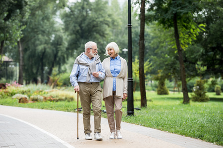 happy senior couple talking while walking in park