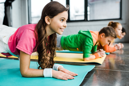 Children doing plank exercise on fitness mats in gymの写真素材