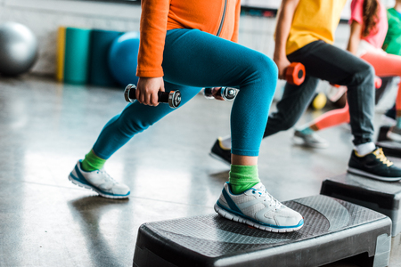 Cropped view of kids standing on step platforms and holding dumbbellsの写真素材