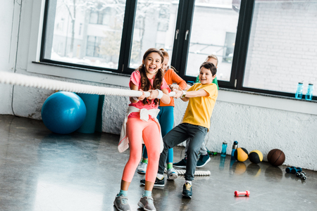 Excited kids playing tug of war in gymの写真素材
