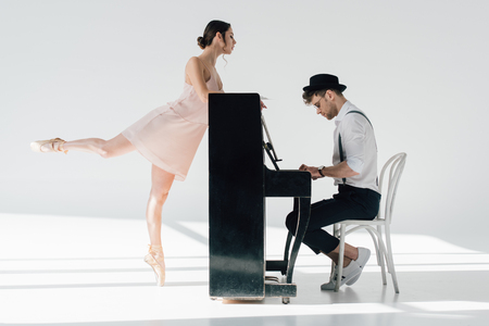 handsome pianist playing while beautiful ballerina dancing near pianoの写真素材