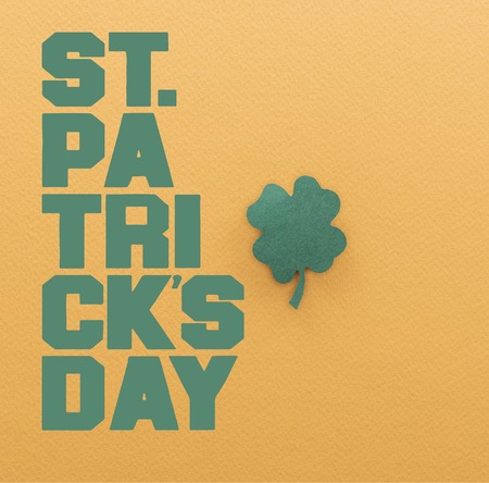 green paper shamrock near st patrick day lettering on orange background