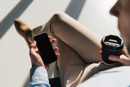 selective focus of man holding smartphone with blank screen and disposable cupの写真素材