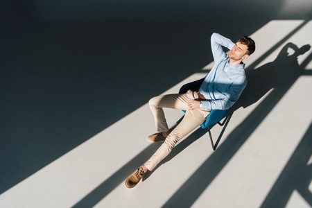 handsome man resting in armchair in sunlightの写真素材