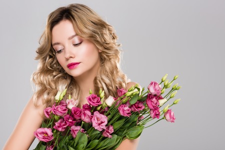 attractive woman with bouquet of Eustoma flowers isolated on greyの写真素材