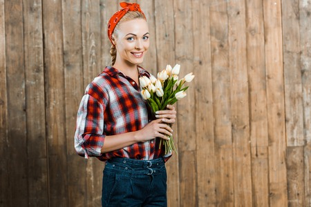 Cheerful woman smiling while holding tulips in hands