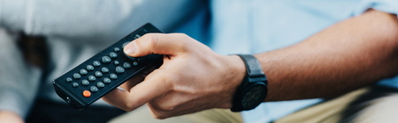 cropped view of man holding remote control in hand
