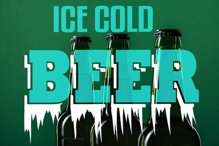 beer bottles near ice cold beer lettering on green backgroundの写真素材