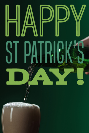 beer pouring into glass with happy st patricks day lettering on green backgroundの写真素材