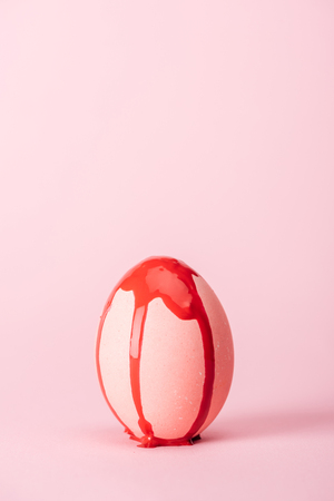 easter egg with red paint spills on pink with copy spaceの写真素材