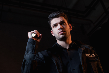 handsome guard in black uniform holding flashlight