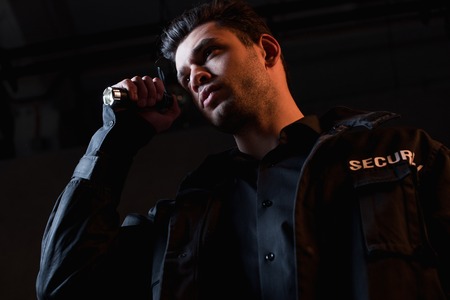 guard in uniform holding flashlight and looking away