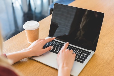 cropped view of woman using laptop with copy space at cafeの写真素材