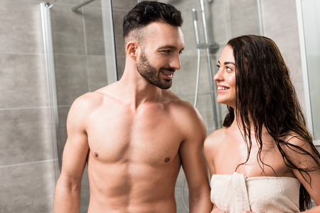 cheerful bearded man looking at smiling brunette woman in bathroomの写真素材