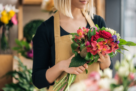 Cropped view of florist in apron holding bouquet in flower shopの写真素材