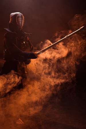 Kendo fighter in armor practicing with bamboo sword in smokeの写真素材