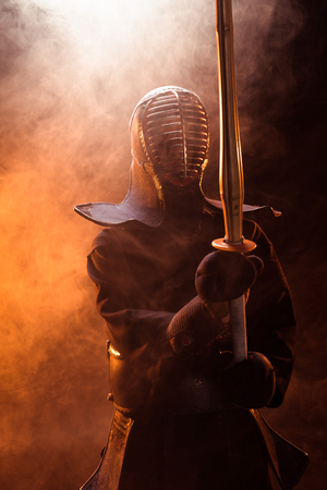 Kendo fighter in armor holding bamboo sword in smokeの写真素材