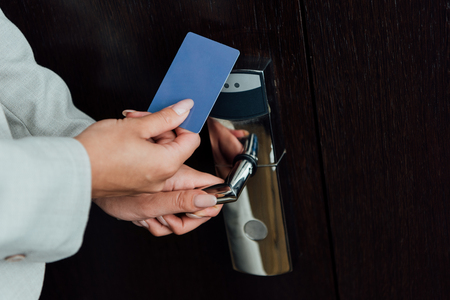 cropped view of woman holding hotel card while opening hotel doorの写真素材