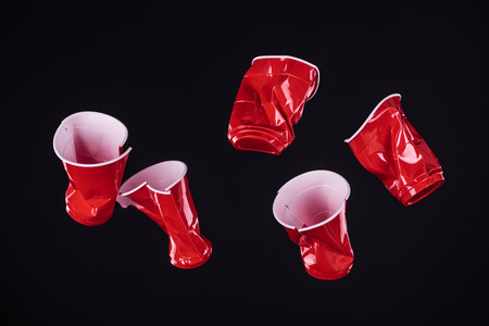 top view of bright and colorful, red plastic cups isolated on black with copy spaceの写真素材