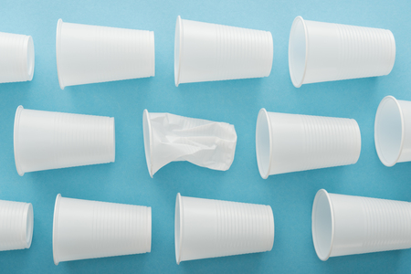 top view of white and crumpledplastic cups on blue background