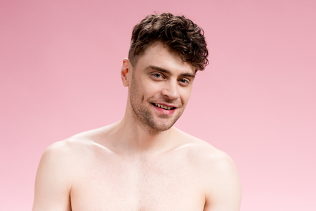 handsome, cheerful brunette man looking at camera on pinkの写真素材