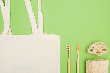 organic bamboo toothbrushes, loofah and cotton bag on light green background