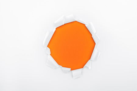 torn hole in white textured paper on orange backgroundの写真素材