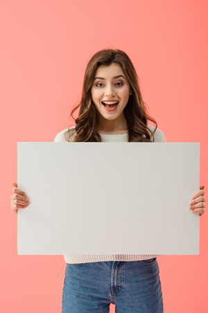 happy and beautiful woman holding empty board with copy space isolated on pinkの写真素材