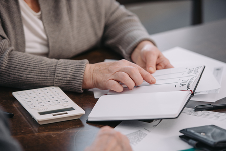 cropped view of senior woman pointing with finger at notebook with ira roth letteringの写真素材