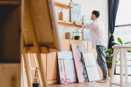 selective focus of artist in white shirt and blue jeans standing in light galleryの写真素材