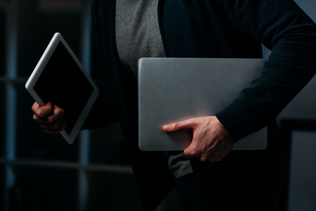 Cropped view of thief stealing digital tablet and laptopの写真素材
