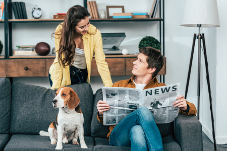 Man with dog reading newspaper on sofa and looking at girlの写真素材