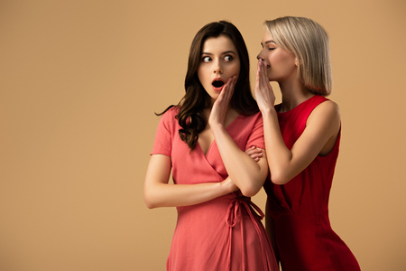 beautiful women in red dresses talking isolated on beige with copy spaceの写真素材