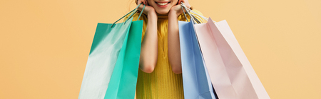 Panoramic shot of laughing girl holding shopping bags isolated on orangeの写真素材