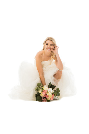 tricky cheerful bride funny grimacing and holding wedding bouquet isolated on whiteの写真素材