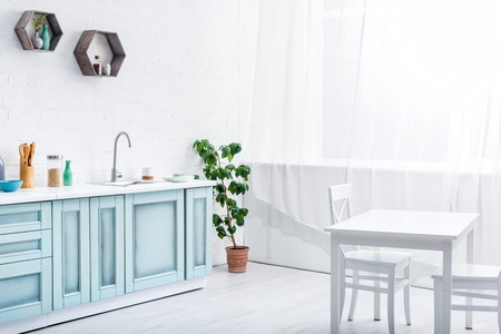 interior of light spacious white and turquoise kitchen with green plantの写真素材