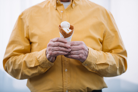 cropped view of senior man holding ice cream coneの写真素材