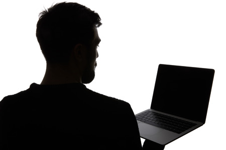 Silhouette of man holding laptop with blank screen isolated on whiteの写真素材