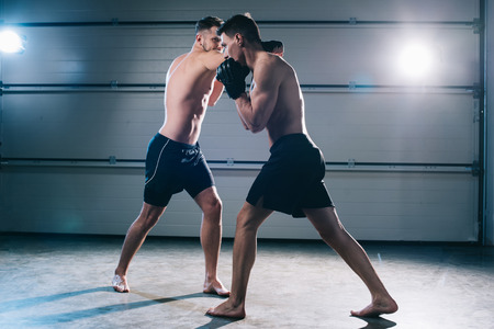 strong shirtless barefoot mma sportsmen fighting while man punching anotherの写真素材