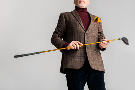 cropped view of trendy mature man holding golf club and while standing isolated on greyの写真素材