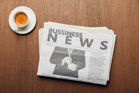 top view of business newspaper near cup with coffee