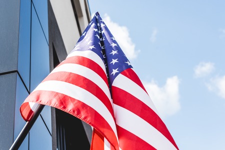 low angle view of national flag of america with stars and stripes near buildingの写真素材